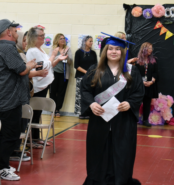 Audience members clap as students receive their certificates