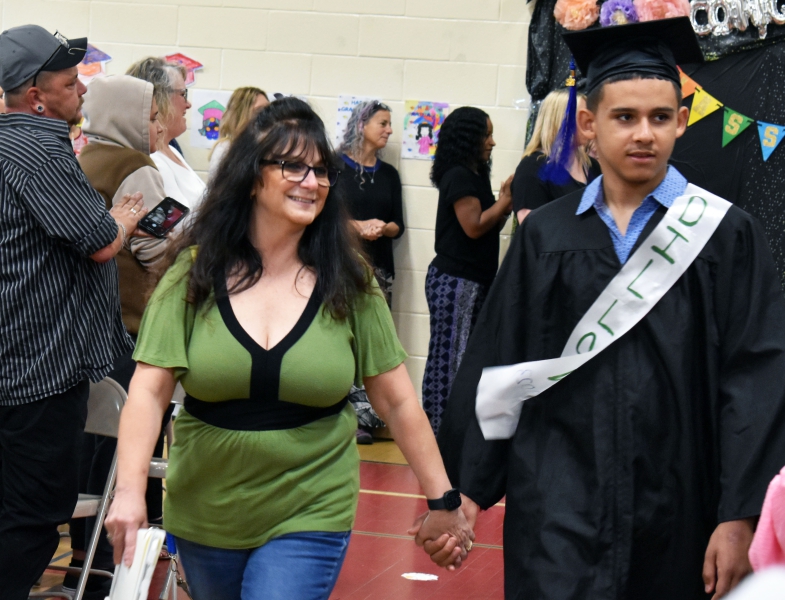 A student walks down the aisle, celebrating his accomplishment.