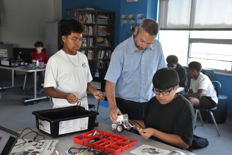 DCC's Dan Barbuto holds a robotic car as students figure out how to finish assembling it.