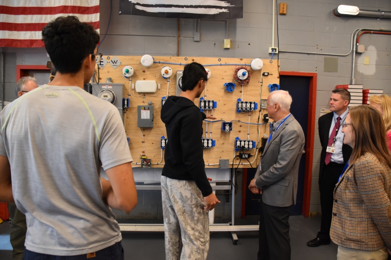 Students in CTI's Trade Electric program talk to members of the Board of Trustees and show them the board of switches they work with.