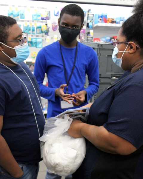 Students Malcom Lewis and Jovan Watt review assignment cards with BOCES job coach Fabienne Simons