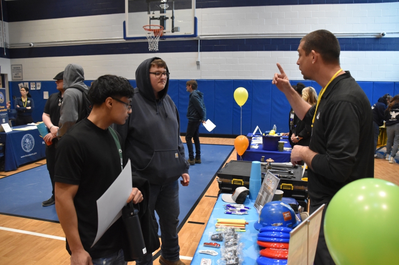 Students speak with a representative of the Sprinkler Fitters union at the Career Exploration Fair at Resilience Academy.