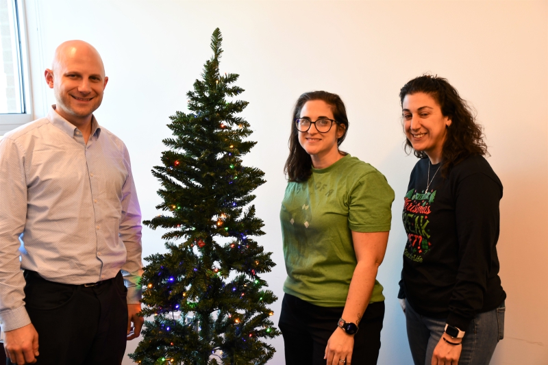 Rob LaColla, Christina Olson and Krystine Nardozzi, members of the Resilience Academy’s PBIS program, stand with one of the two trees in the conference that no longer have gift tags for staff to purchase gifts for students and their families in need.