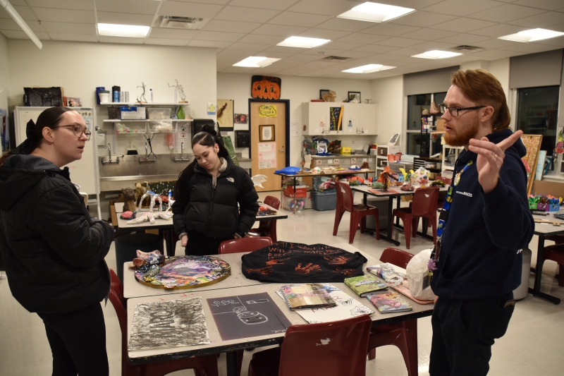 Theresa Knapp reviews her daughter's (Isabella Ramos) art work with Teacher Michael Hollick at the Resilience Academy Open House.