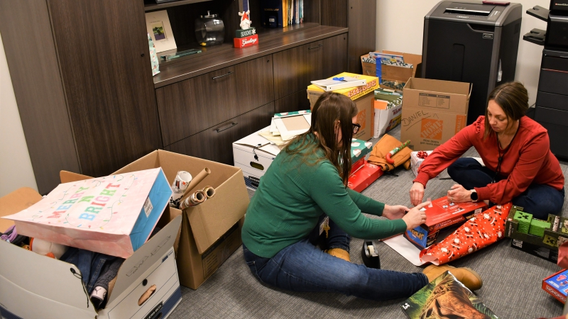 Members of the administration team wrap gifts for adopted families.