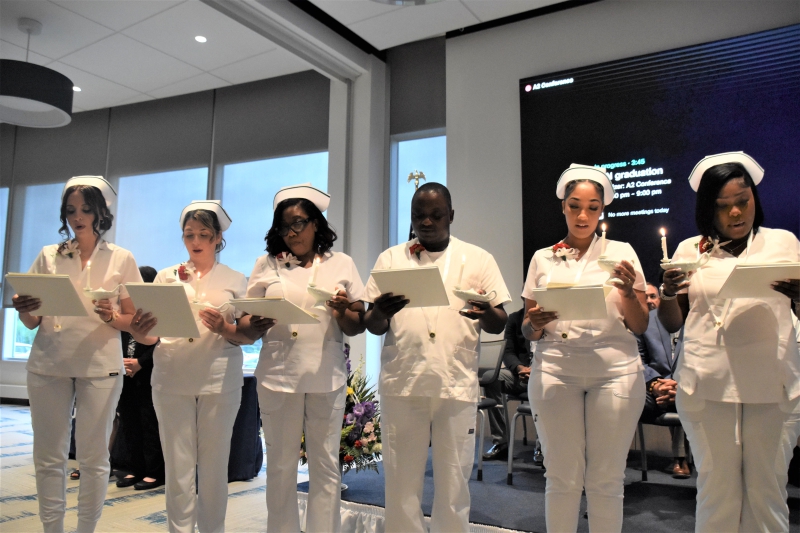 Graduates recite the Florence Nightingale Pledge, holding lamps with candles, symbolizing Nightingale's oil lamp.