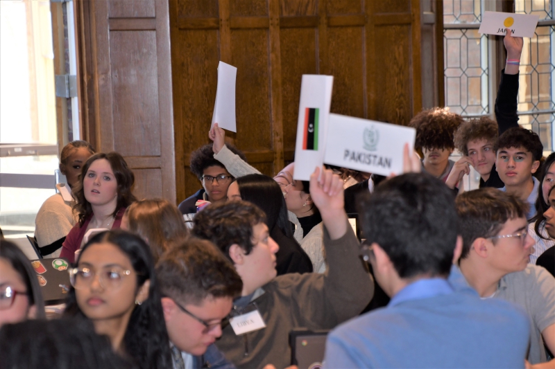 The student delegates hold up signs representing their assigned country.