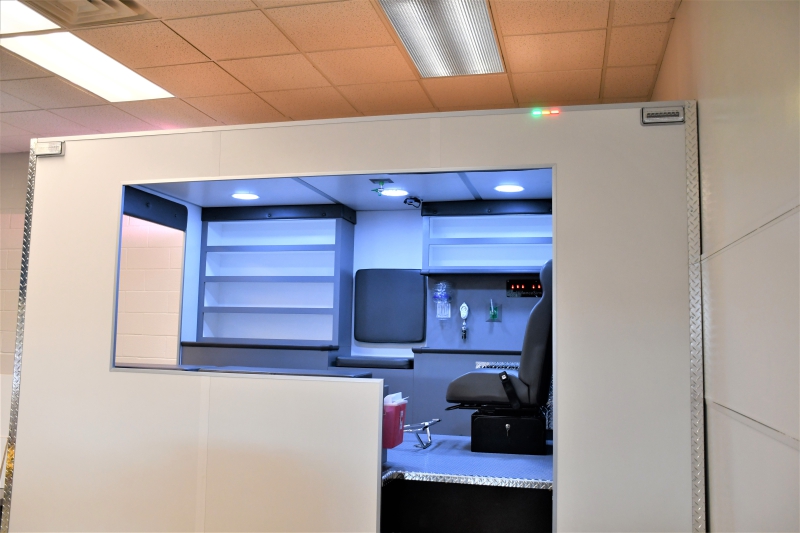 A side view of the simulator showing the flashing lights, seat, oxygen panel, jump seat and place for a stretcher.