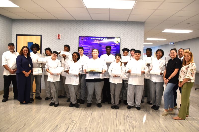 Culinary Arts and Restaurant Management students pose with teachers, administrators and staff as they deliver boxes of cookies before the board meeting