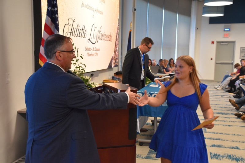 Juliette Wisniewski shakes hands with Director of Career and Technical Education and Adult Learning Nicholas Millas after receiving her award.
