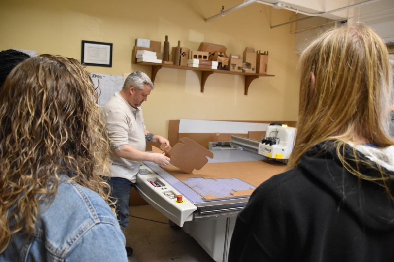 Viking Lead Designer Eric Lesh shows CTI Graphic Design students a finished box after it was cut out on a Kongsberg cutting table.