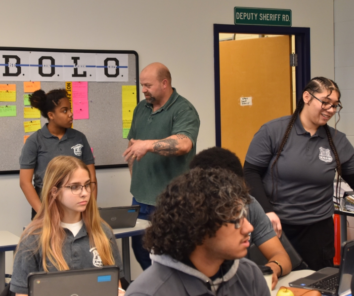 Security and Law Teacher Stephen Price speaks with a student during class. Price used artificial intelligence to create scenarios for students to help them practice making arrests and doing the paperwork.