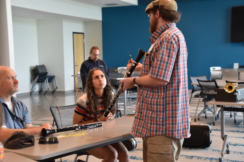 Paul Effman Music repair tech Wes Stier holds a clarinet and a tool, demonstrating how to make a repair to during the workshop.