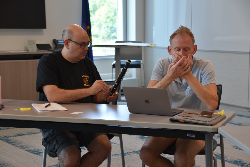 Music educators sit at a table with pieces of a clarinet in hand and make minor repairs they learned how to do during the workshop.