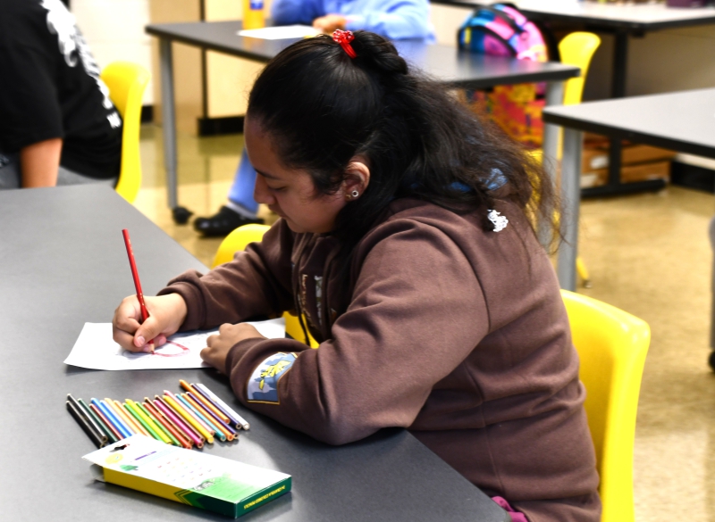SPC student Dania colors a red heart as part of a mural for Hispanic Heritage Month