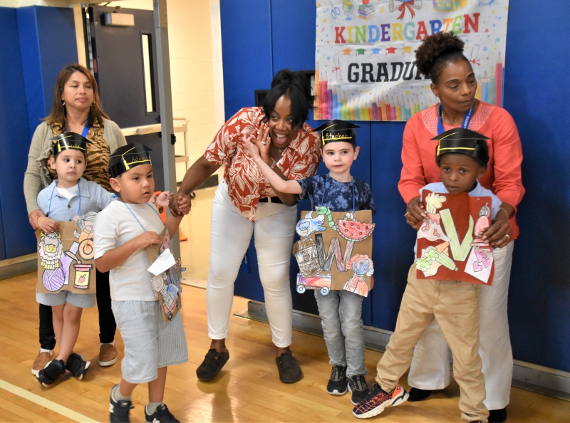 Students and staff wave to families as they enter the Salt Point Center gym for the Kindergarten Moving Up Day and Alphabet Parade.