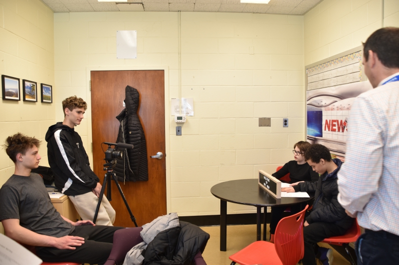 SPC students sit behind the 'news' desk at SPC as they prepare for the recording of the April 6 edition of SPC news. Two CTI TV and Film students are across from them behind a camera on a tripod..