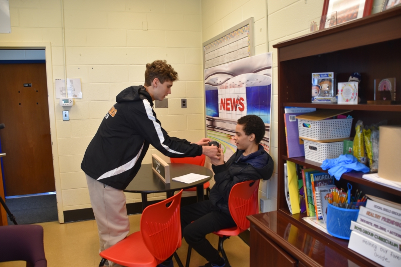 A CTI student hands SPC student Ethan Horton the camera being used to record the show.